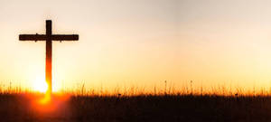 Red Sunrise Behind A Lone Cross Wallpaper