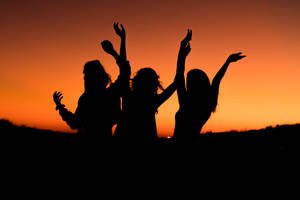 Silhouette Of Three Woman With Hands On The Air While Dancing During Sunset Wallpaper
