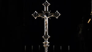 Silver Jesus Cross In Dim Room Wallpaper