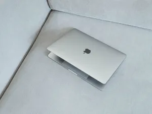Silver Macbook On White Fabric Sofa Wallpaper