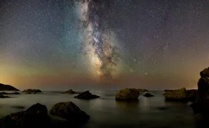 Star Sky Over Rocky Body Of Water Wallpaper