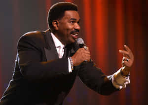 Steve Harvey With A Tuxedo And Microphone Wallpaper