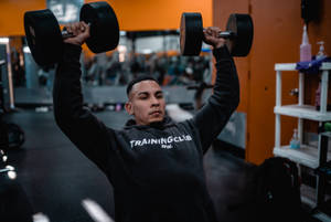 Strong Man Lifting Dumbbells In Gym Wallpaper