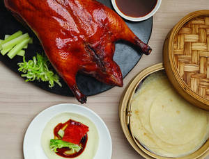 Succulent Roasted Peking Duck Served On A Stylish Black Platter Wallpaper