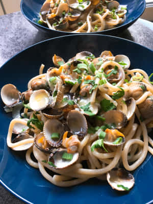 Sumptuous Spaghetti Alla Vongole Served On A Blue Plate Wallpaper