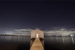 Take In The Beautiful View Of A House On A Tranquil Body Of Water. Wallpaper