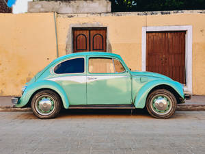 Teal Volkswagen Beetle Parked Near Brown House Wallpaper