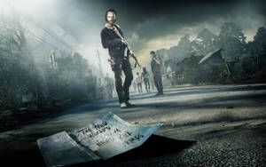 Tense Moment In The Walking Dead With A Mysterious Note On The Ground Wallpaper