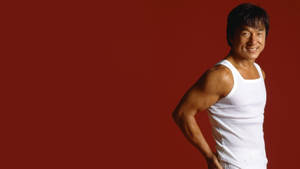 The Irrepressible Jackie Chan In A White Tank Top Wallpaper