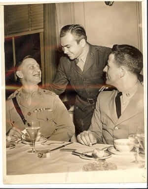 Three Men In Uniforms Sitting At A Table Wallpaper