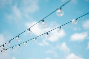 Tilt Lens Photography Of String Lights Under Cloudy Skies Wallpaper