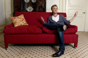 Tom Felton On Red Couch Wallpaper