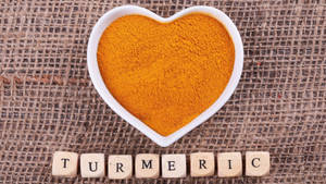 Turmeric Powder In Heart-shaped Bowl Wallpaper