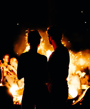 Two Persons Standing In Front Of Bonfire Wallpaper