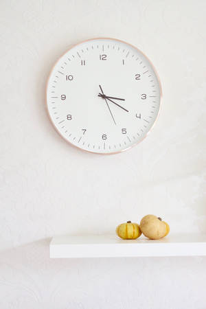 Two Pumpkins On Table Below Wall Clock Wallpaper