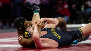 Two Wrestlers Grapple During Intense Freestyle Wrestling Match Wallpaper