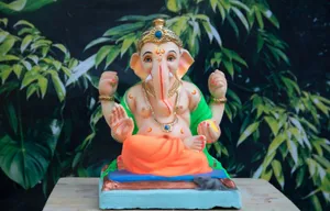Vinayaka Figurine In Green And Orange Clothes Wallpaper