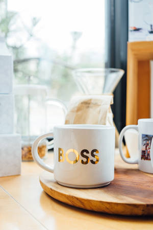 White Boss-printed Ceramic Mug On Brown Surface Wallpaper
