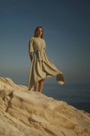 Woman In Brown Dress Standing On Brown Rock Formation During Daytime Wallpaper