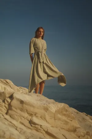 Woman In Brown Dress Standing On Brown Rock Formation During Daytime Wallpaper