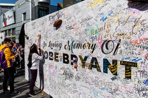 Woman In White Long Sleeve Shirt And Black Pants Standing Beside Wall With Graffiti During Daytime Wallpaper