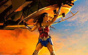 Wonder Woman Powerfully Lifting A Tank. Wallpaper