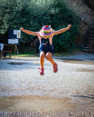 Young Girl Jumping In Puddle Wallpaper