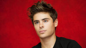 Zac Efron Looking Suave In A Red Backdrop Wallpaper